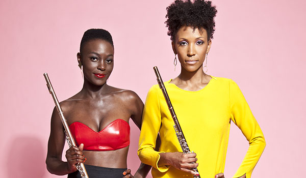 Two women in bright clothing pose with their flutes.