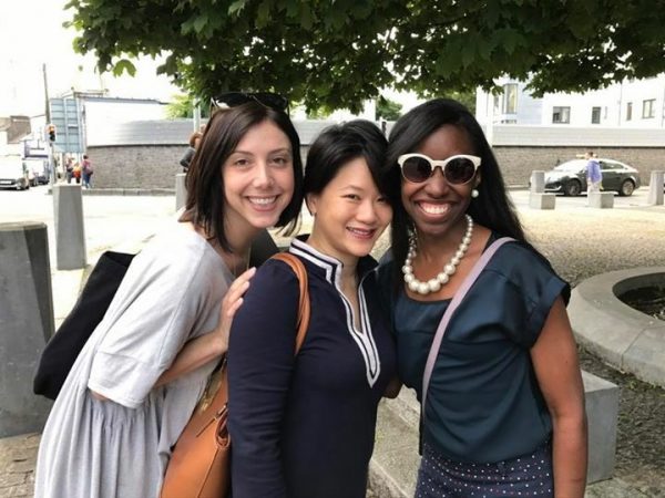 Three women pose together outside on an international business trip
